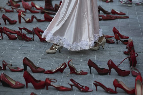 An actress walks near a line of red shoes representing murdered women, as part of a performance during the national women&#039;s strike &quot;A Day Without Women&quot; in Mexico City, Monday, March 9, ...