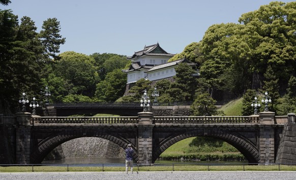epa08421083 A person takes a photo at the outer garden plaza of the Imperial Palace during a coronavirus state of emergency, in Tokyo Japan, 14 May 2020. Japanese Prime Minister Shinzo Abe is expected ...