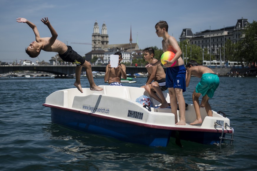 Junge Maenner kuehlen sich mit einem Sprung vom Pedalo in den Zuerichsee ab, aufgenommen am Samstag, 19. Juli 2014 in Zuerich. (KEYSTONE/Ennio Leanza)

Young men jump from a Pedalo boat into the Lak ...