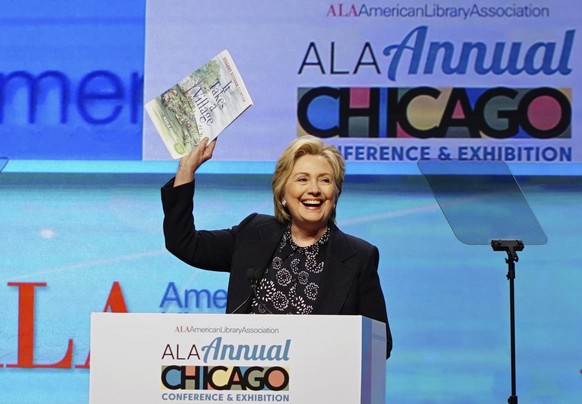 Hillary Clinton holds up an illustrated children&#039;s version of her book, &#039;It Takes a Village&#039;, as she speaks at the American Library Association (ALA) Annual Conference and Exhibition, T ...