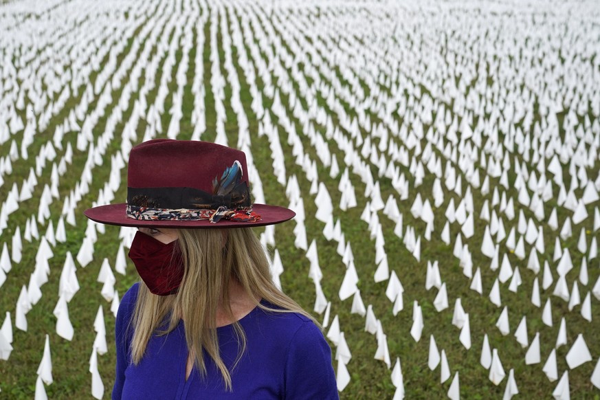 Artist Suzanne Brennan Firstenberg stands among thousands of white flags planted in remembrance of Americans who have died of COVID-19, Tuesday, Oct. 27, 2020, near Robert F. Kennedy Memorial Stadium  ...