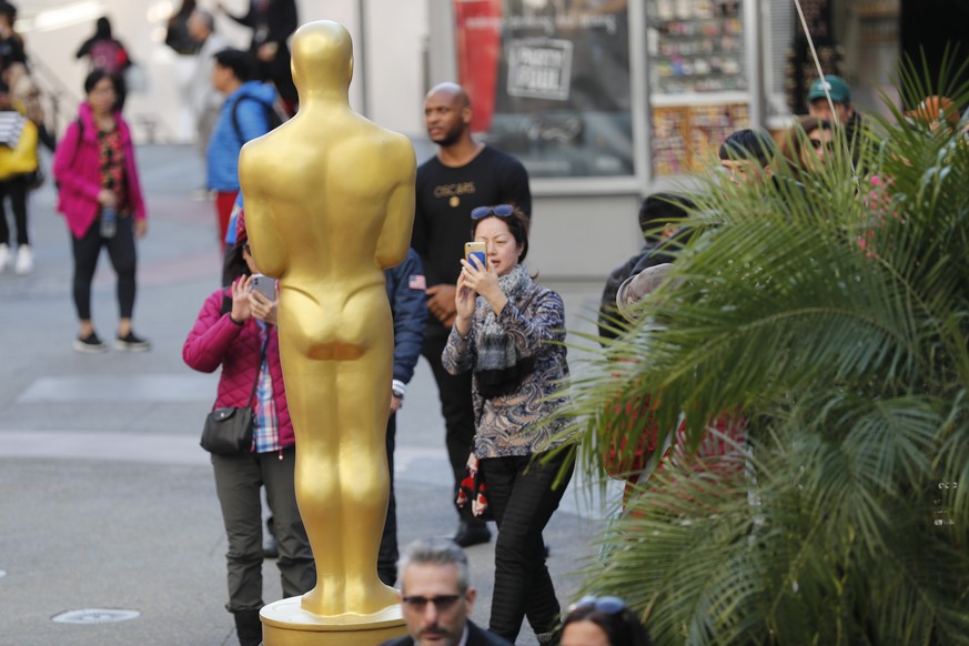 epa08201503 People take photos of an Oscar statue near the red carpet for the 92nd annual Academy Awards ceremony at the Dolby Theatre in Hollywood, California, USA, 07 February 2020. The Oscars are p ...