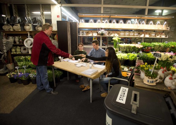 epa04131713 Early voters cast their ballot in a flower shop furnished as a polling station for the Dutch municipal council elections at the railway station of Castricum, The Netherlands, 19 March 2014 ...