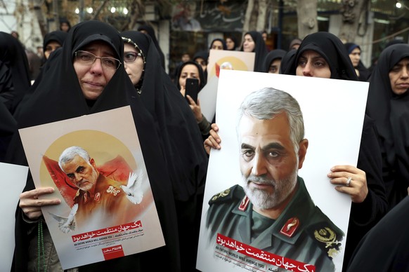 Protesters hold up posters of Gen. Qassem Soleimani while mourning during a demonstration over the U.S. airstrike in Iraq that killed Iranian Revolutionary Guard Gen. Qassem Soleimani, in Tehran, Iran ...
