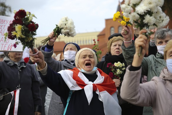 People, most of them pensioners, wave bunches of flowers during an opposition rally to protest the official presidential election results in Minsk, Belarus, Monday, Oct. 26, 2020. Factory workers, stu ...