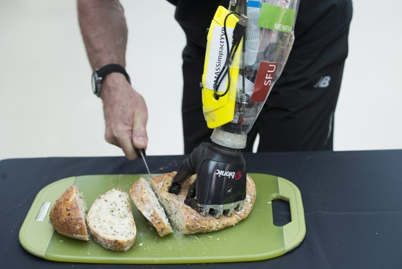 Danny Letain uses a bionic hand to help him cut bread at Simon Fraser University in Burnaby, Canada, Tuesday, May 3, 2016. When Letain lost his hand in a workplace accident 35 years ago, he never imag ...