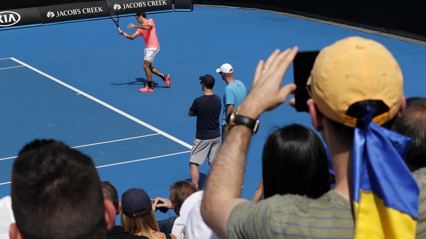 Spectators watch as Switzerland&#039;s Roger Federer hits a forehand return during a practice session at the Australian Open tennis championships in Melbourne, Australia, Saturday, Jan. 27, 2018. Fede ...