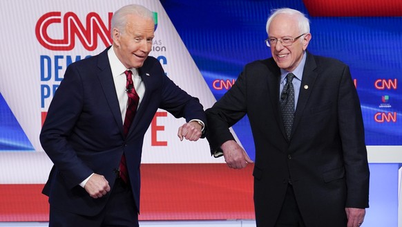 Former Vice President Joe Biden, left, and Sen. Bernie Sanders, I-Vt., right, greet each other before they participate in a Democratic presidential primary debate at CNN Studios in Washington, Sunday, ...