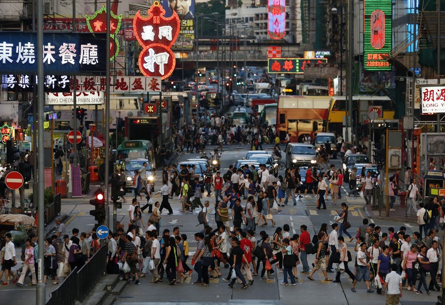 In this Sept. 10, 2014, photo, pedestrians cross the road in the Hong Kong shopping district of Mongkok during rush hour. On packed subways and crowded streets, billions of people worldwide participat ...