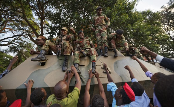 Zimbabweans reach out to touch and thank army soldiers, as they celebrate outside the parliament building immediately after hearing the news that President Robert Mugabe had resigned, in downtown Hara ...
