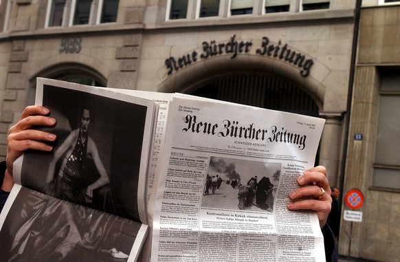 Ein Mann liest am Freitag, 11. April 2003, die Neue Zuercher Zeitung, gegenueber dem NZZ-Sitz, an der Falkenstrasse in Zuerich. Die NZZ-Gruppe ist letztes Jahr mit 50 Millionen Franken in die roten Za ...