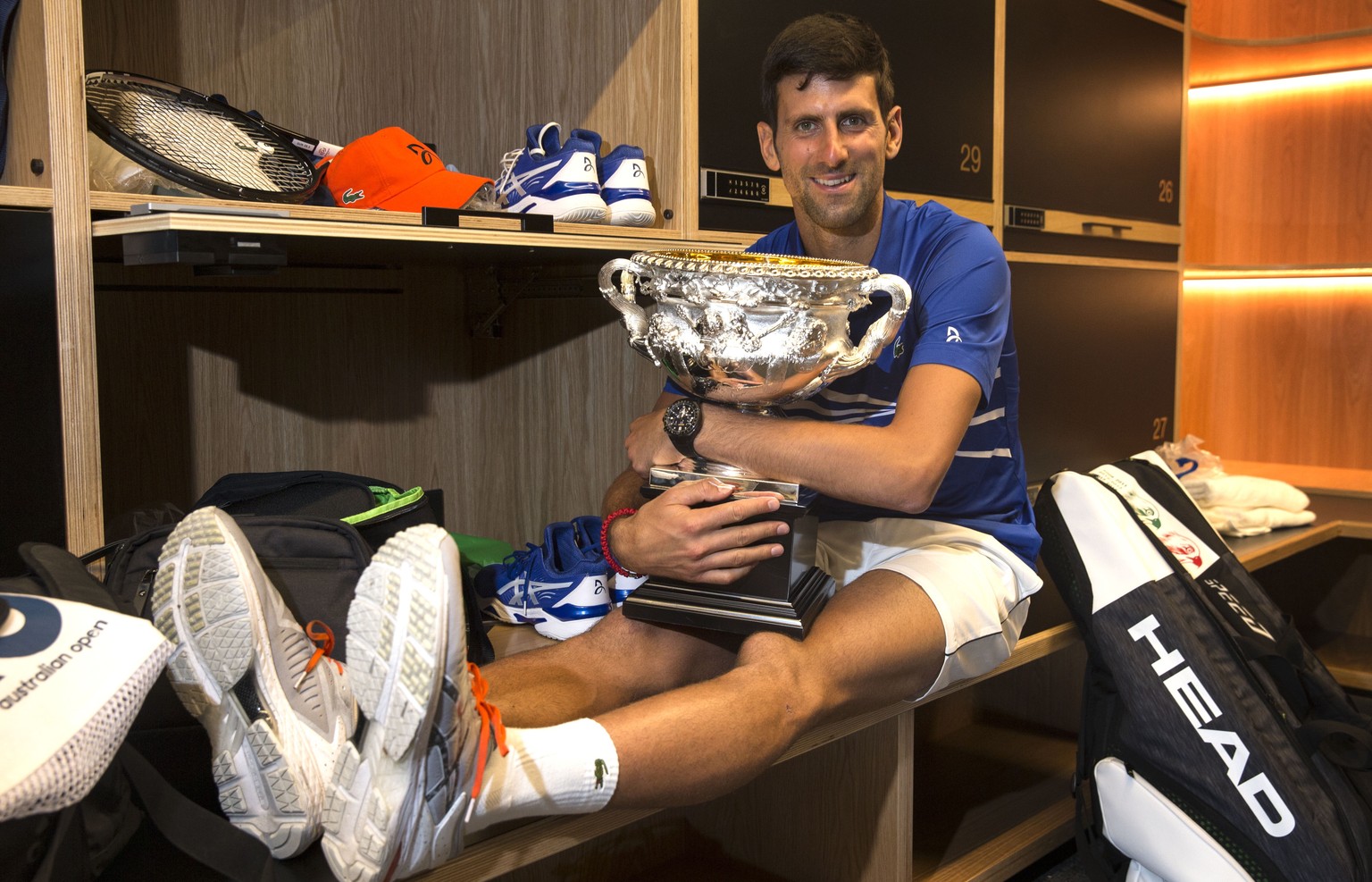 epa07324779 A handout photo made available by TENNIS AUSTRALIA shows Novak Djokovic of Serbia posing with the winner&#039;s trophy, the Norman Brookes Challenge Cup, in the mens locker room after defe ...
