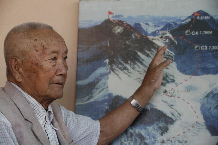 In this Tuesday, April 11, 2017 photo, Nepalese climber Min Bahadur Sherchan, points to a picture to describe the trail to Mount Everest, as he talks to Associated Press at his residence in Kathmandu, ...