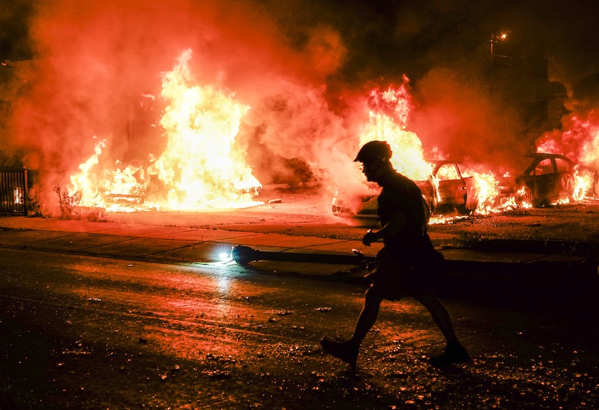 epa08623798 A man is silhouetted against a burning business during a second night of unrest in the wake of the shooting of Jacob Blake by police officers, in Kenosha, Wisconsin, USA, 25 August 2020. A ...