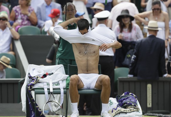 Novak Djokovic of Serbia changes his shirt in a game break during the men&#039;s quarterfinal match against Kei Nishikori of Japan at the Wimbledon Tennis Championships in London, Wednesday July 11, 2 ...