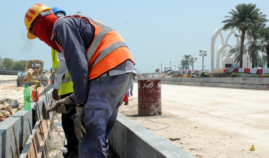 epa03895985 Foreign laborers work at the construction site for a new corniche road in Doha, Qatar, 04 October 2013. Recent media reports said immigrant workers on projects for the World Cup 2022 have  ...