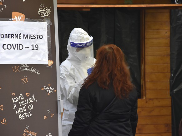 Ein Mediziner in Schutzkleidung macht an einer Corona-Teststation einen Abstrich bei einer Frau. In der Slowakei werden die Corona-Massentests fortgesetzt. Foto: Miroslava Mlyn