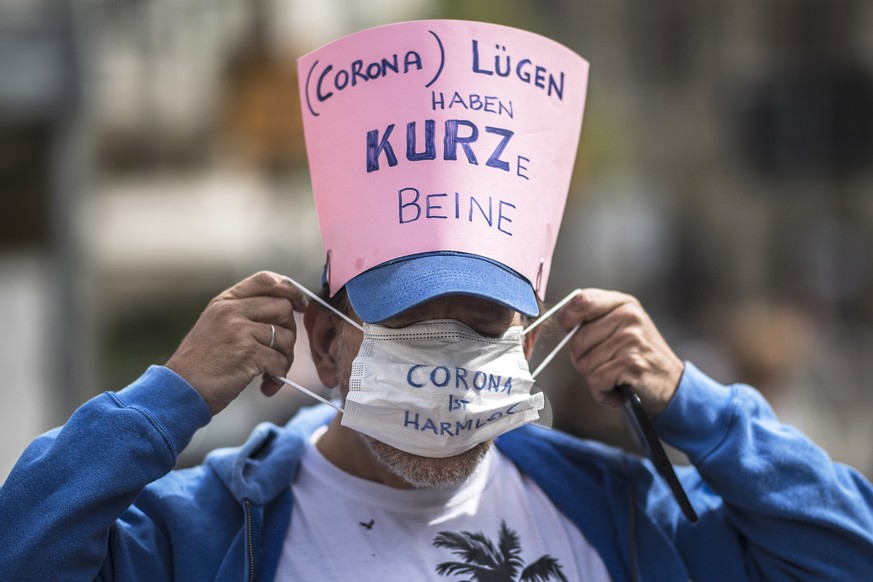 epa08382459 A participant puts on a protective face mask reading &#039;Corona is harmless&#039; as he wears a sign reading &#039;(Corona) Lies have short legs&#039; referring to Austrian Chancellor Se ...