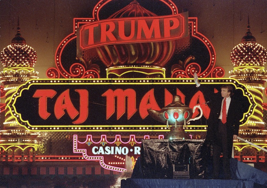 FILE - In this April 5, 1990 file photo, Donald Trump stands next to a genie&#039;s lamp as the lights of his Trump Taj Mahal Casino Resort light up during ceremonies to mark its opening in Atlantic C ...