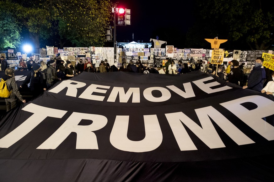 epa08797255 People hold a banner that reads &#039;Remove Trump&#039;, at Black Lives Matter Plaza near the White House, seen behind, in Washington, DC, USA, 03 November 2020. Americans vote on Electio ...