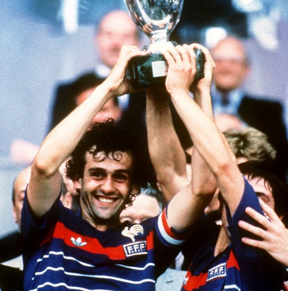 Frankreichs Mittelfeldregisseur und Kapitaen Michel Platini, links, und sein Teamgefaehrte Alain Giresse halten am 27. Juli 1984 im Pariser Prinzenpark-Stadion jubelnd den Henri-Delaunay-Pokal hoch. F ...