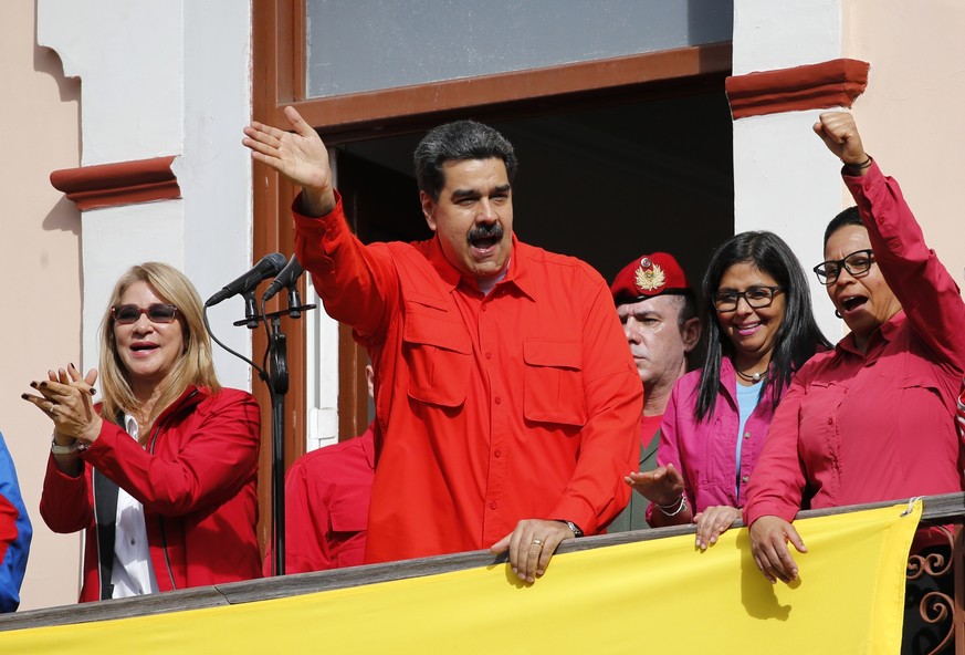 Venezuela&#039;s President Nicolas Maduro, center, and first lady Cilia Flores, left, interact with supporters from a balcony at Miraflores presidential palace during a rally in Caracas, Venezuela, We ...