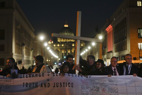 Survivors of sex abuse hold a cross as they gather in front of Via della Conciliazione, the road leading to St. Peter&#039;s Square, visible in background, during a twilight vigil prayer of the victim ...