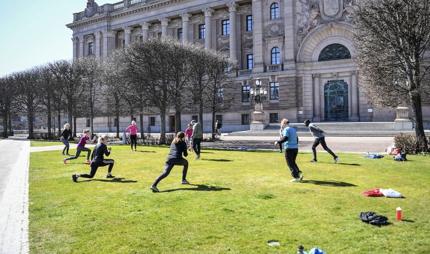epa08375305 People exercise on a lawn, keeping distance amid the coronavirus disease (COVID-19) outbreak, outside the old parliament building in central Stockholm, Sweden, 21 April 2020. EPA/Fredrik S ...