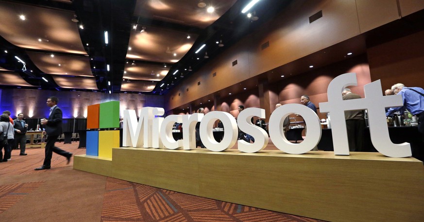 File-This Nov. 30, 2016, file photo shows a man walking past a Microsoft sign at the annual Microsoft shareholders meeting in Bellevue, Wash. U.S. stocks moved broadly lower in morning trading Tuesday ...