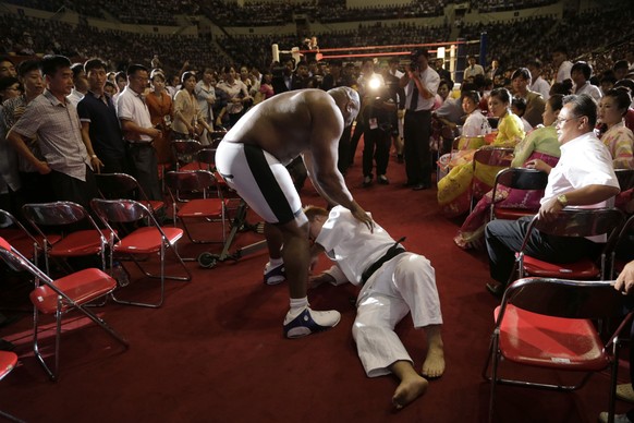 North Koreans watch as Bob &quot;The Beast&quot; Sapp, center left, struggles with his opponent during a pro wrestling exhibition, Sunday, Aug. 31, 2014 in Pyongyang, North Korea. (AP Photo/Kim Kwang  ...