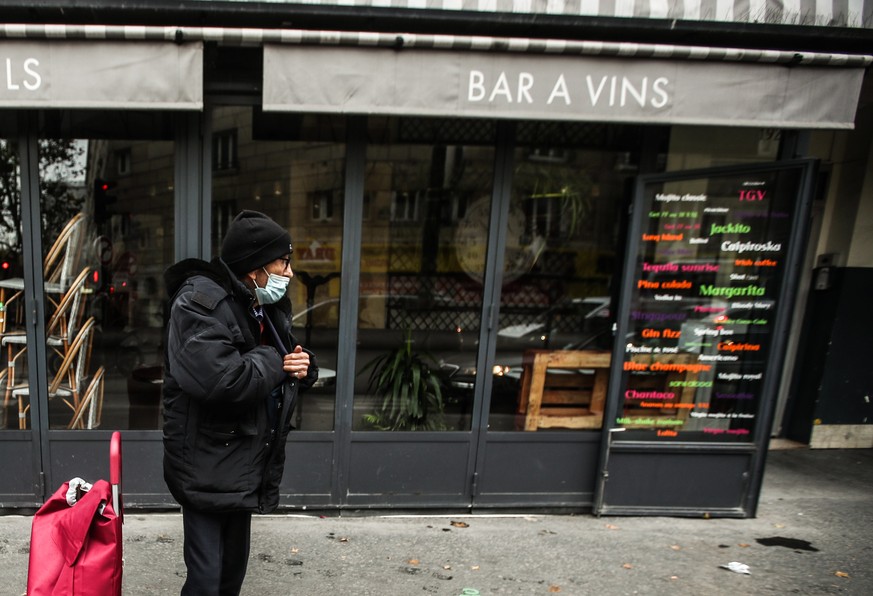 epa08811989 An elderly man wearing a face mask, stands next to a closed restaurant, in Paris, France, 10 November 2020. France re-intoduced lockdown measures in the midst of a second wave of the COVID ...