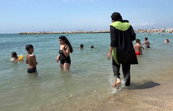 FILE - In this Aug.4 2016 file photo made from video, Nissrine Samali, 20, gets into the sea wearing traditional Islamic dress, in Marseille, southern France. The French resort of Cannes has banned fu ...