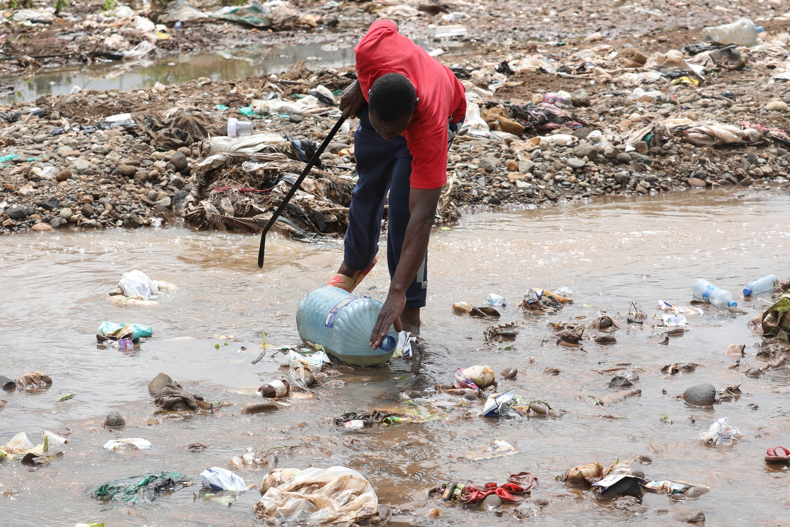 epa06762122 A volunteer collects plastic waste during a clean-up exercise organised by UN Environment near the Nairobi Dam in Kibera slum, Nairobi, Kenya, 25 May 2018. A clean-up and tree-planting eve ...