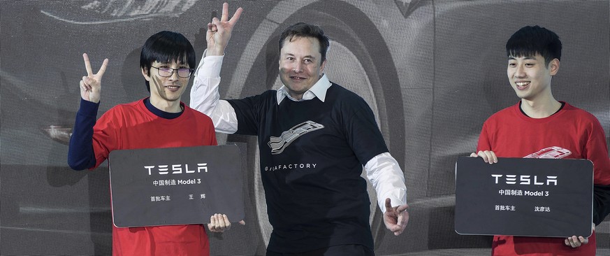 In this photo released by China&#039;s Xinhua News Agency, Tesla CEO Elon Musk, center, poses with Tesla owners at a delivery ceremony for the first Tesla Model 3 cars made at Tesla&#039;s Shanghai fa ...