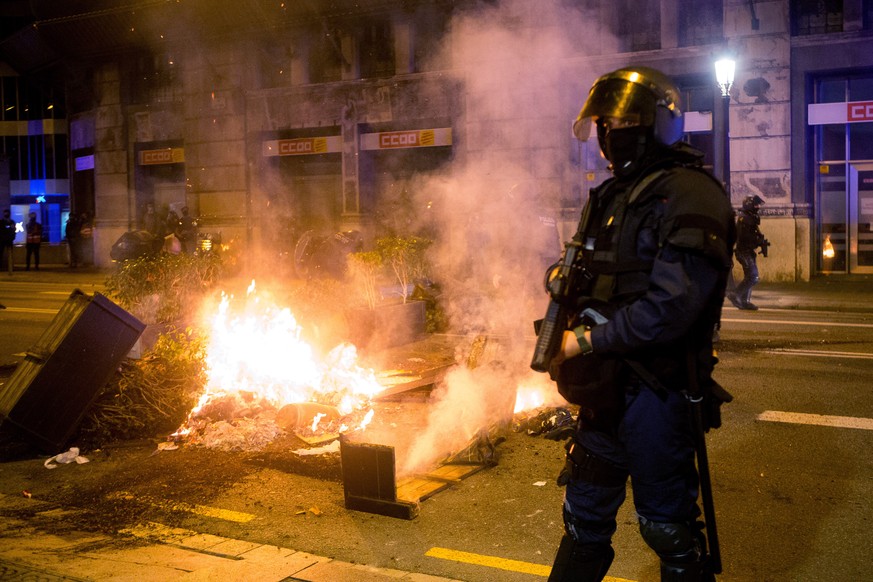 epa08786939 Mossos d&#039;Esquadra agents stand guard as COVID-19 deniers burn urban furniture during a march to protest against the restrictions imposed to fight against the coronavirus pandemic, in  ...