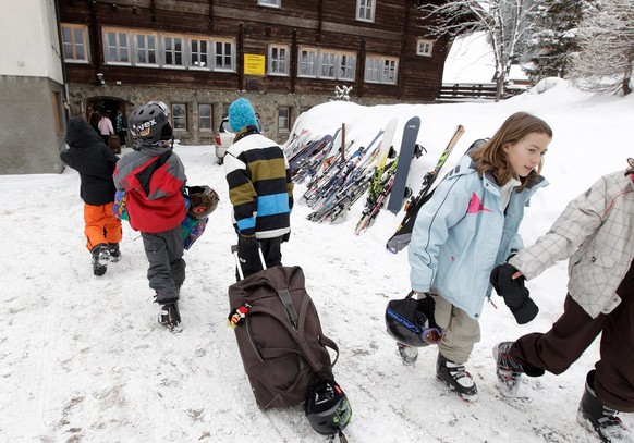 Schulkinder aus dem Zuercher Unterland schleppen am Sonntag, 27. Februar 2011, ihre Koffer zum Von-Sprecher-Haus am Davosersee in Davos, wo sie ihre Sportferien in den kommenden sieben Tagen verbringe ...