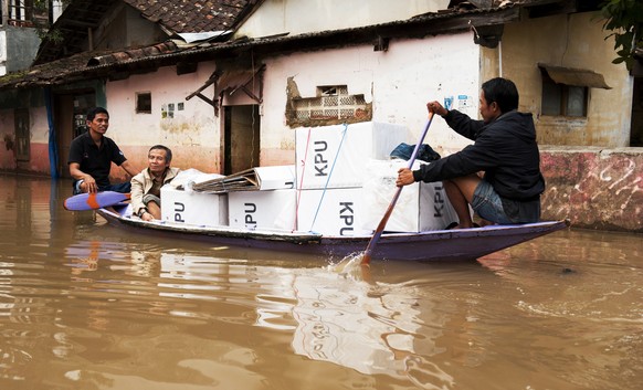 epa07535649 Indonesian election officials transport ballot boxes from polling stations on a boat as they wade through flood water in Bandung, West Java, Indonesia, 18 April 2019 (issued 29 April 2019) ...