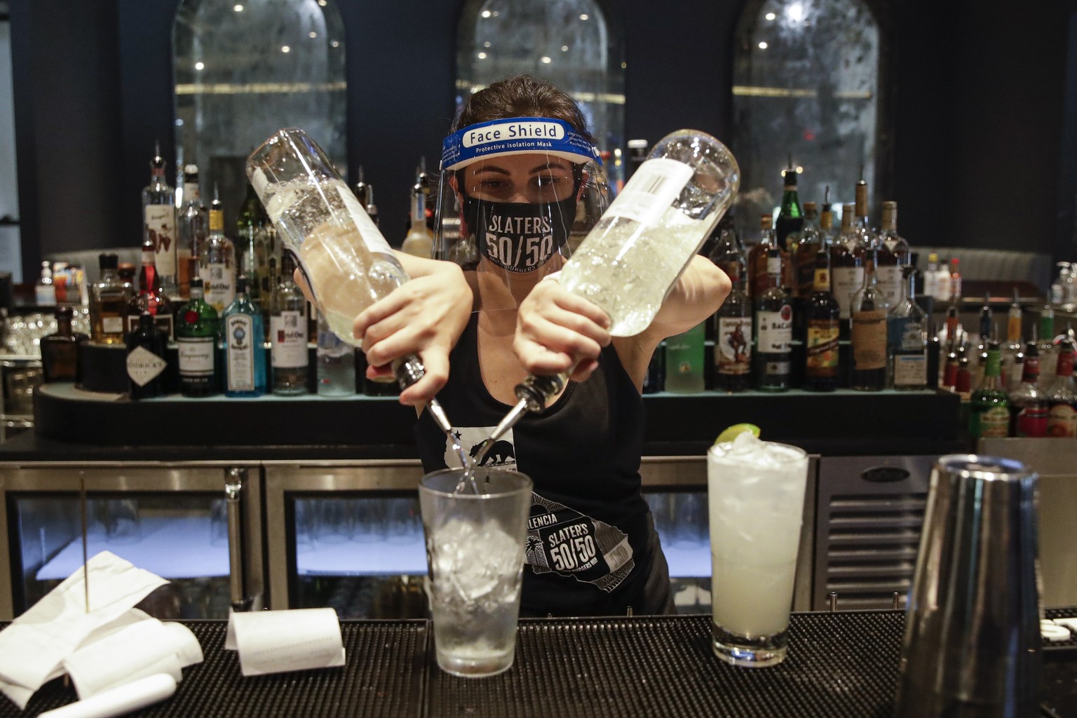 A bartender mixes a drink while wearing a mask and face shield at Slater&#039;s 50/50 Wednesday, July 1, 2020, in Santa Clarita, Calif. California Gov. Gavin Newsom has ordered a three-week closure of ...
