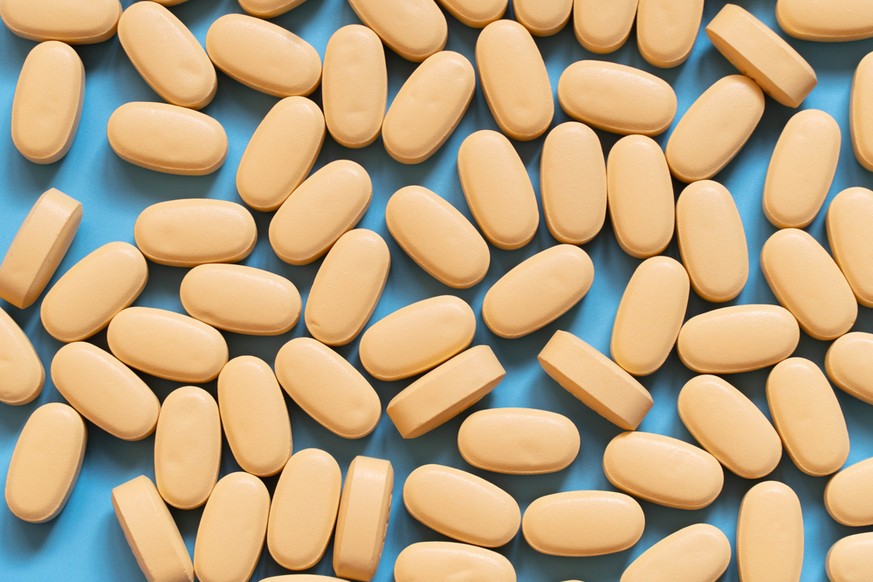 Tablette mit gelben Medikamenten auf blauem Hintergrund. Lopinavir/Ritonavir Kombinationstabletten (Kaletra) zur Behandlung und Prävention von HIV/AIDS.