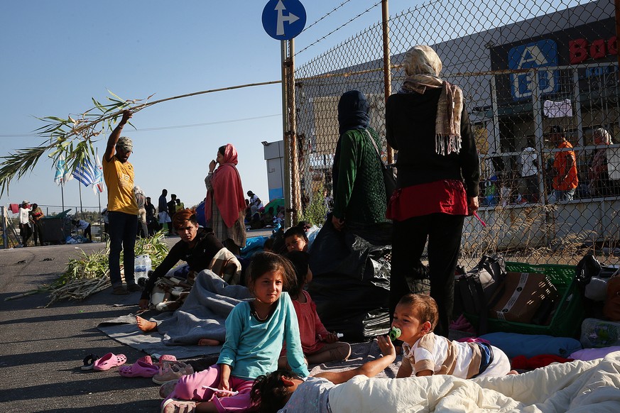 epa08660644 Asylum seekers rest on a roadside, near the Moria refugees camp destroyed in a fire on 09 September, Lesbos island, Greece, 11 September 2020. A fire broke out in the overcrowded Moria Ref ...