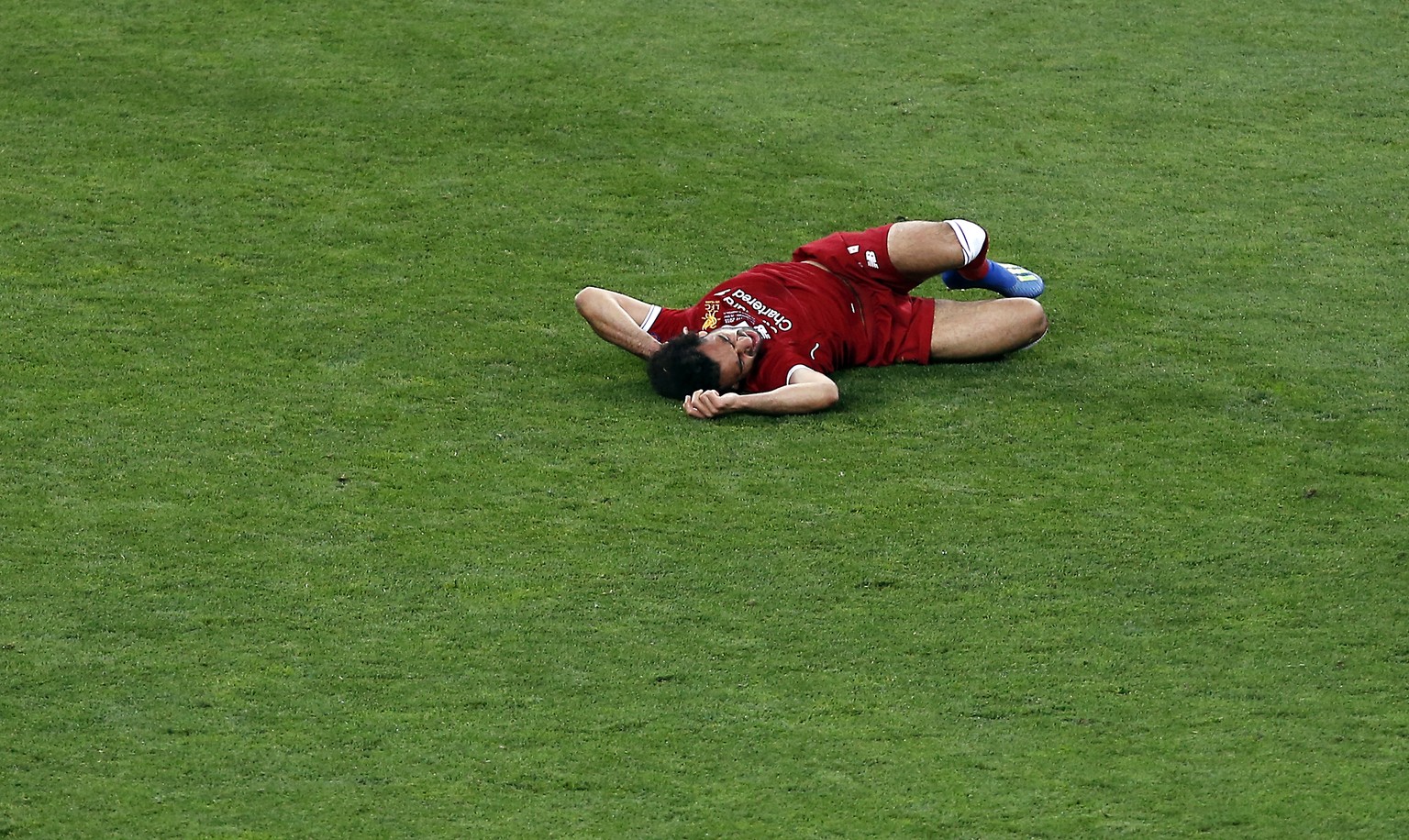 Liverpool&#039;s Mohamed Salah lies on the pitch after a collision with Real Madrid&#039;s Sergio Ramos during the Champions League Final soccer match between Real Madrid and Liverpool at the Olimpiys ...