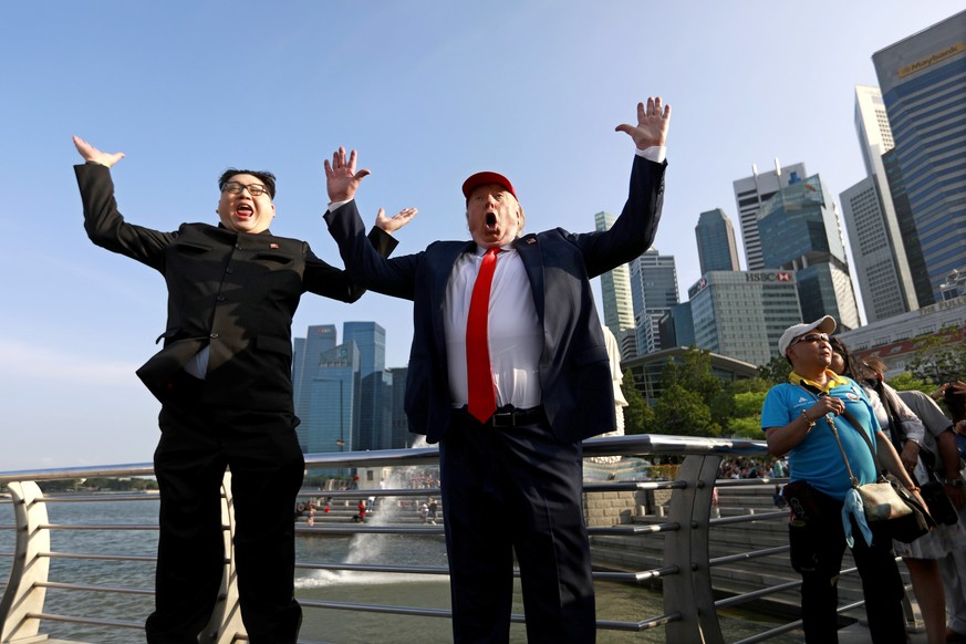 epa06792891 Kim Jong-Un impersonator Howard X (L) and Donald Trump impersonator Dennis Alan jumps for a photo at the Merlion Park in Singapore, 08 June 2018. US President Donald J. Trump and North Kor ...