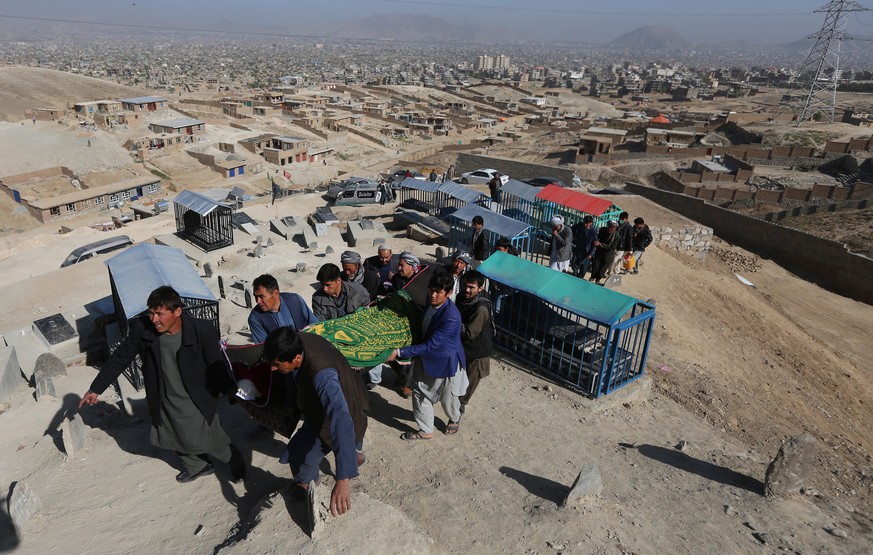 epa08772088 Afghan men carry a dead body of a young student toward the grave yard a day after a suicide attack targeted an education center in Kabul, Afghanistan, 25 October 2020. At least 26 people w ...