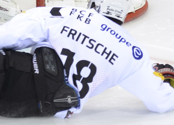 Le joueur fribourgeois, John Fritsche, droite, a la lutte pour le puck avec le gardien genevois, Robert Mayer, gauche, lors du match du championnat suisse de hockey sur glace de National League LNA, e ...