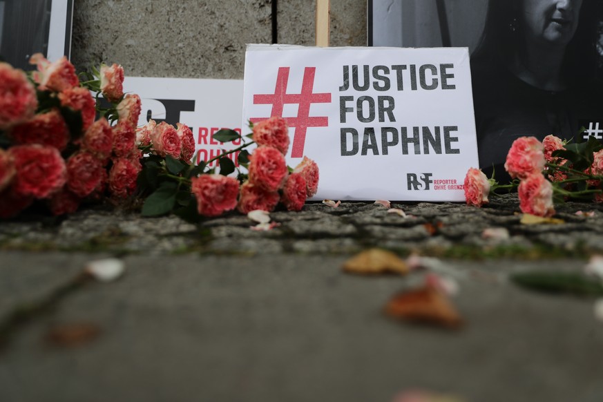 epa08749854 Flowers and placards reading &#039;Justice for Daphne&#039; are seen at a vigil on the third anniversary of the murder of the Maltese investigative journalist Daphne Caruana Galizia in fro ...