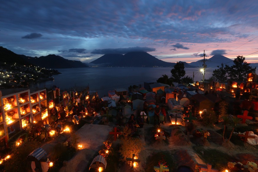 epaselect epa05613522 Locals decorate graves with candles and flowers in a cemetery at the bank of Atitlan lake in San Antonio Palopo, Guatemala, 01 November 2016. EPA/ESTEBAN BIBA