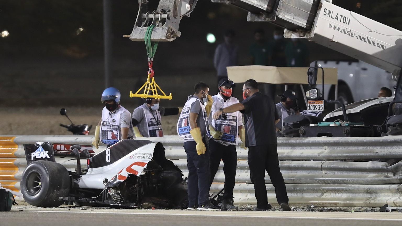 epa08850962 Track marshals remove parts of the car from the crash site of French Formula One driver Romain Grosjean of the Haas F1 Team during the start of the Formula One Grand of Bahrain on the Bahr ...