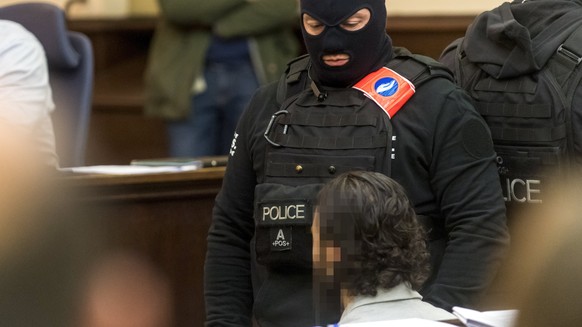 epa06497778 Prime suspect in the November 2015 Paris attacks Salah Abdeslam (R) sits as he is surrounded by Belgian special police officers in the courtroom prior to the opening of the trial of terror ...
