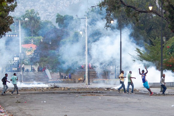 epa08982909 Haitian protesters react as the tear gas is fired by police in the Champs de Mars square, in front of the National Palace, in Port-au-Prince, Haiti, 02 February 2021. Activities came to a  ...