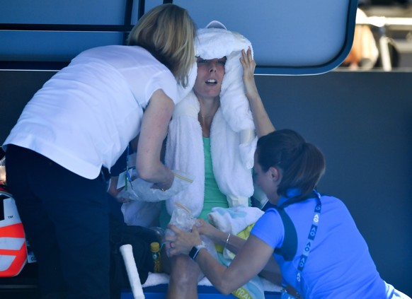 France&#039;s Alize Cornet is attended to by a trainer and tournament staff after suffering from the heat during her third round match against Belgium&#039;s Elise Mertens at the Australian Open tenni ...